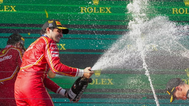 Ferrari driver Carlos Sainz of Spain sprays champagne as he...