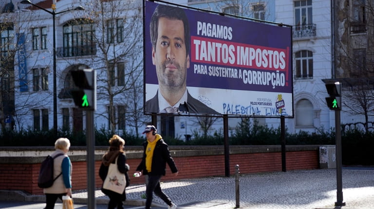 People walk by a billboard for Andre Ventura, leader of...