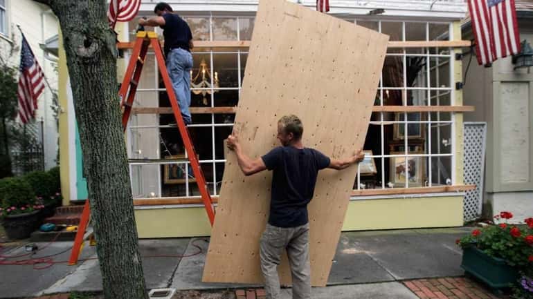Roman Alvarez (L) and Bob Alvarez use plywood to secure...