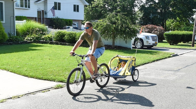 Tom Przybylowski rides a bicycle with his son Konrad, 1, in...