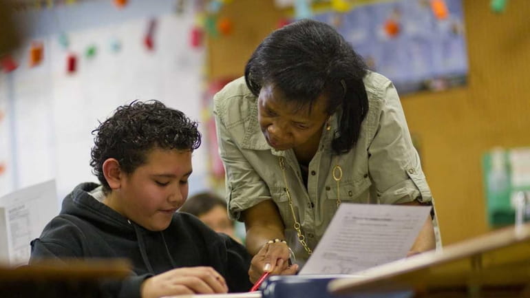 Eighth grade teacher Beverly Robinson helps a student at the...