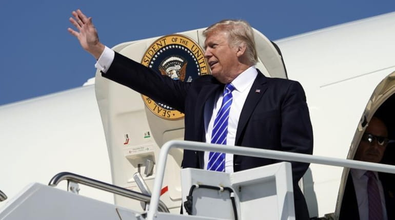 President Donald Trump waves during his arrival at Bismarck Municipal...