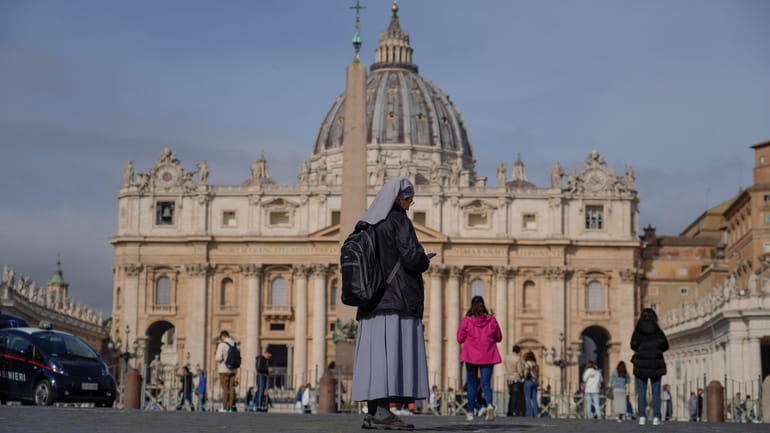 A nun checks her phone in front of St. Peter's...