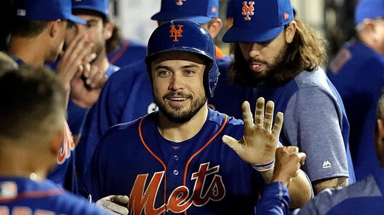 Mets catcher Travis d'Arnaud receives congratulations in the dugout after...