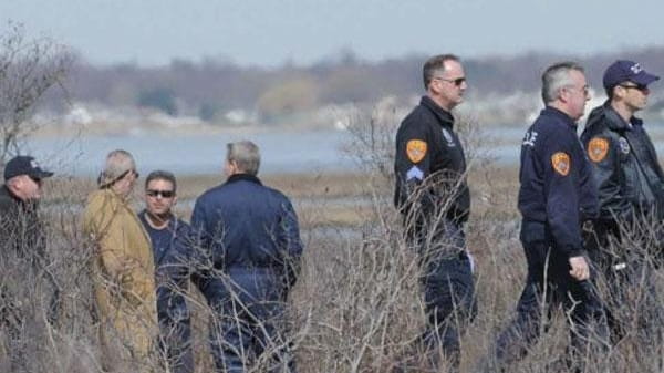 Detectives and investigators probe an area west of Cedar Beach...