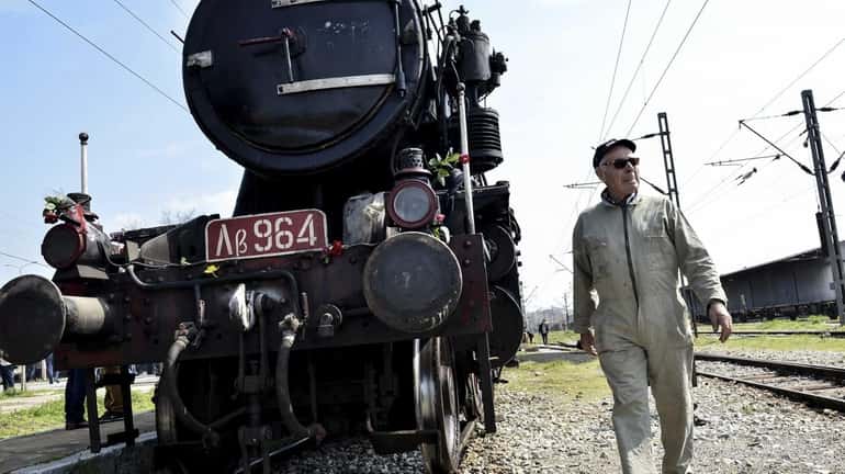 A Hellenic Railway officer walks in front of a train...