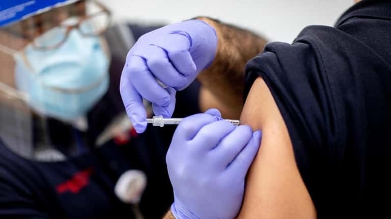 EMT-paramedic Ian Mauro administers the vaccine at Stony Brook University Hospital...