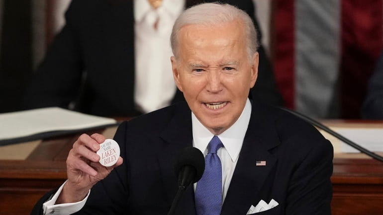 President Joe Biden holds up a Lken Riley button as...