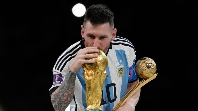 Argentina's Lionel Messi lisses the trophy after winning the World...
