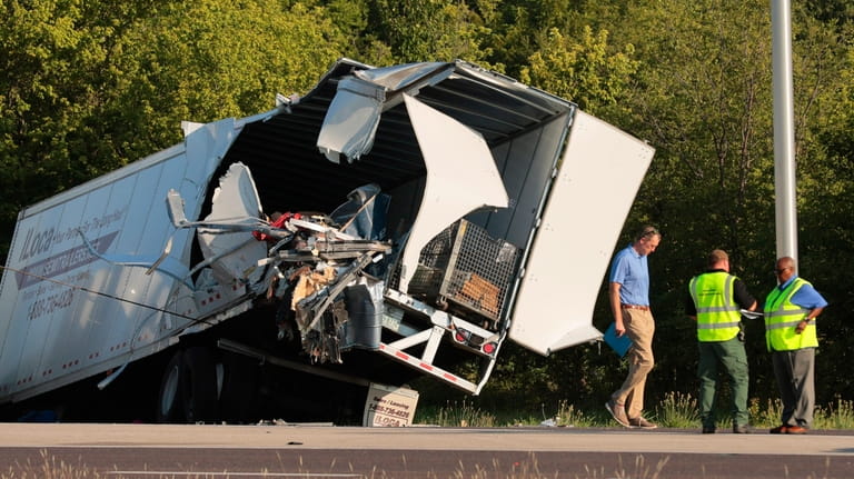 Officials survey a damaged tractor-trailer before removing it from the...