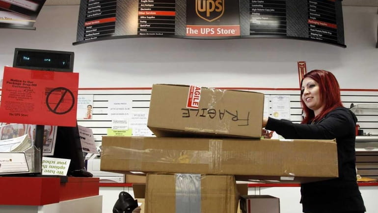UPS store employee Candy Mojica weighs packages before shipping at...