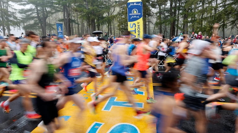 Runners cross the starting line during the 127th Boston Marathon,...