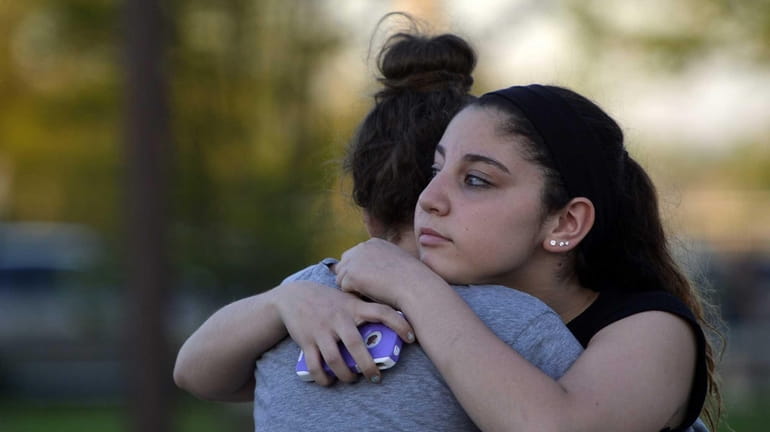Kayla Olsen, 14, right, hugs a friend before a candlelight...