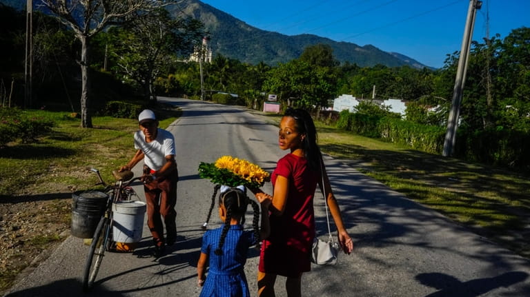 Dainet Cala and her daughter Evelyn carry flowers to leave...