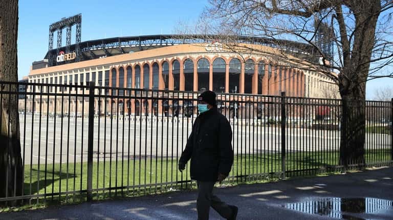 A pedestrian passes a closed Citi Field on the scheduled date for...