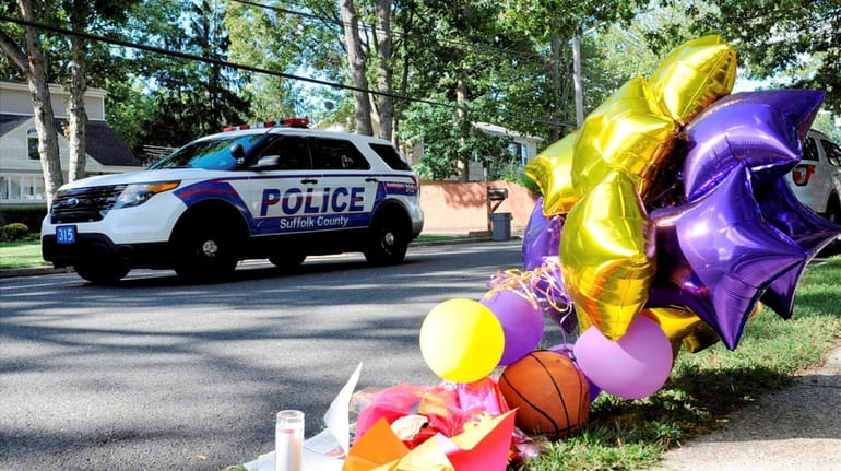 A police vehicle drives by a makeshift memorial on Thursday,...
