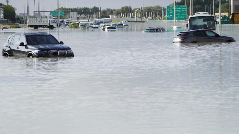 Vehicles sit abandoned in floodwater covering a major road in...