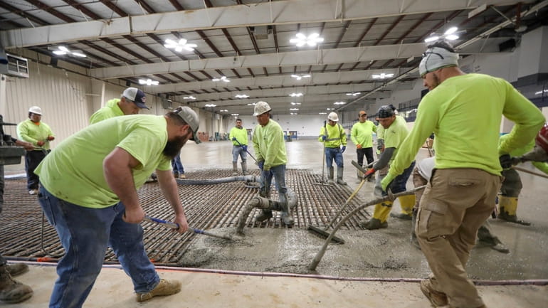 Workers on Wednesday finish pouring cement for the new floor...