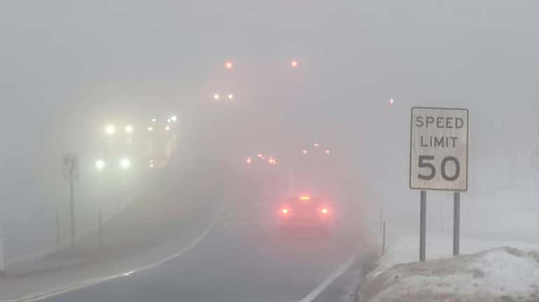 Vehicles travel along Horseblock Road in Medford as dense fog...