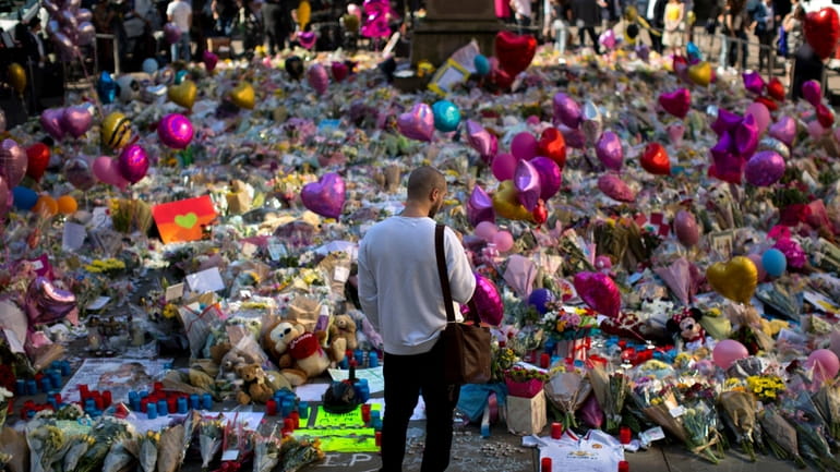A man stands next to flowers for the victims of...