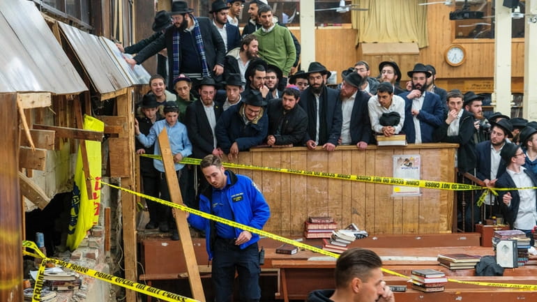 Hasidic Jewish students observe as law enforcement establishes a perimeter...