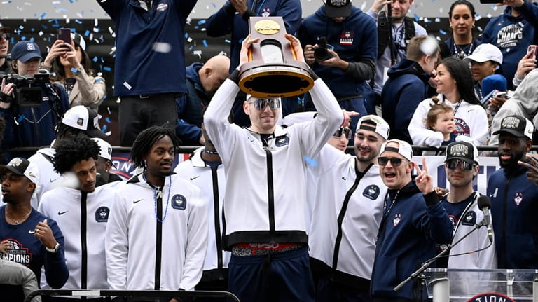 UConn's Donovan Clingan holds up the championship trophy as he...