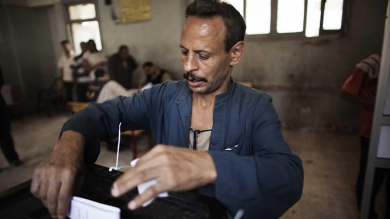 An Egyptian man casts his ballot at a polling station...