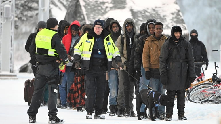 Finnish Border Guards escort migrants at the international border crossing...