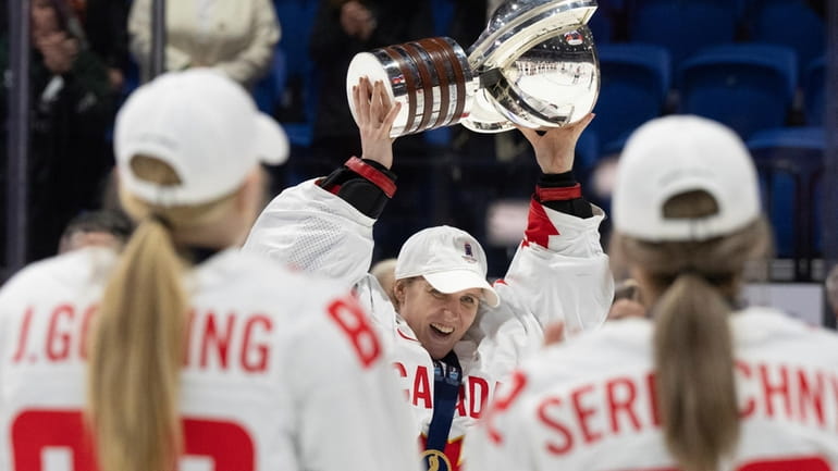 Canada goaltender Ann-Renee Desbiens (35) hoists the trophy following their...