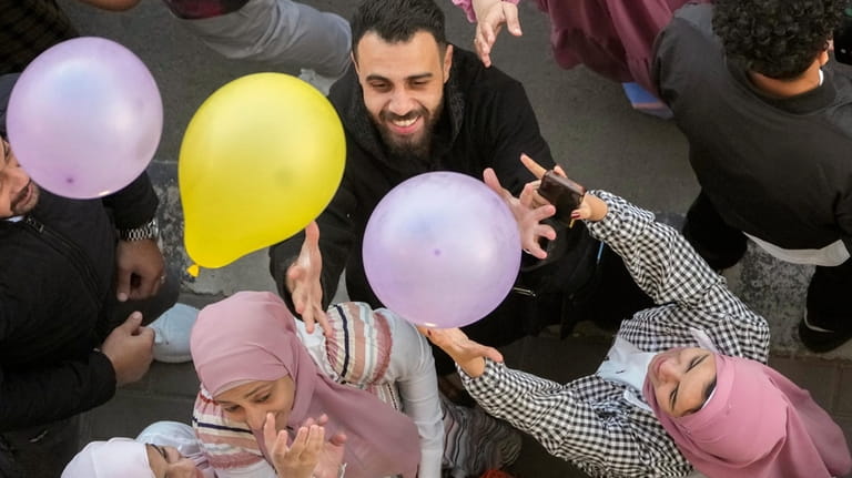 Muslims try to catch balloons distributed after Eid al-Fitr prayers,...