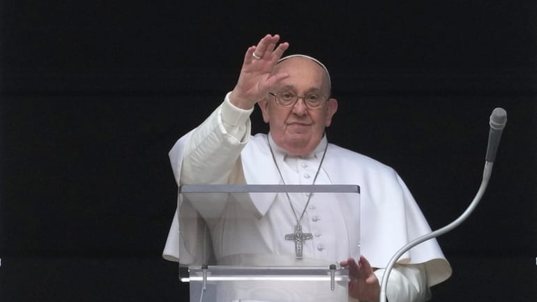 Pope Francis waves during the Angelus noon prayer from the...