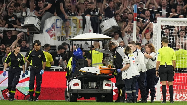 Lyon's Alexandre Lacazette is carried injured out of the pitch...
