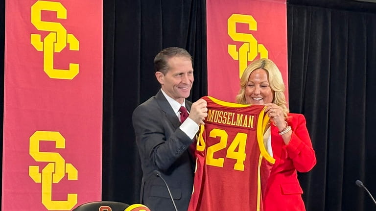 Eric Musselman, left, holds a jersey next to athletic director...