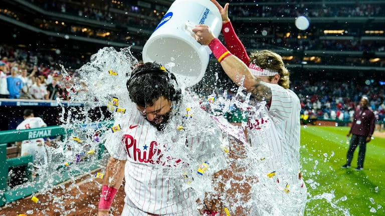 Philadelphia Phillies' Kyle Schwarber, front left, is doused by teammates...