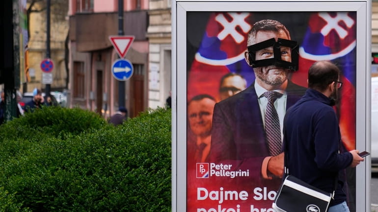A man walks past a poster for Peter Pellegrini, who...