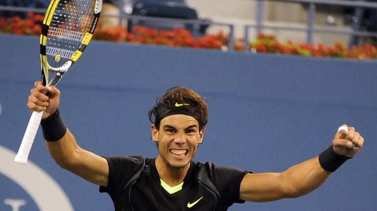 Rafael Nadal holds up his arms in victory after defeating...