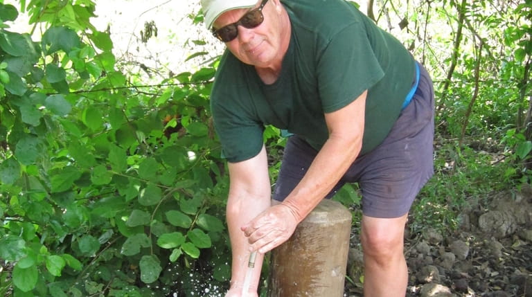 Peter White holds his hands in front of the water spigot...