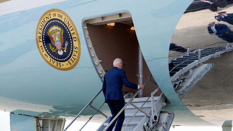 President Joe Biden walks up the steps of Air Force...