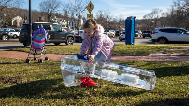 Annalise Bartone, 4, of Holbrook, plays ice sculpture corn hole...