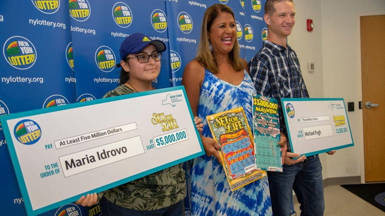 New York Lottery's Yolanda Vega, center, presents checks to lottery winners...