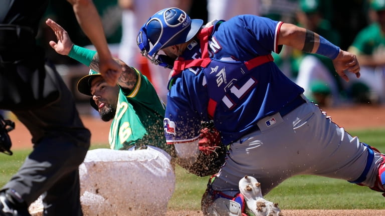 Texas Rangers catcher Sandy Leon, right, tags out Oakland Athletics'...