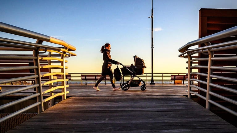 A woman pushes a stroller while walking on the boardwalk...