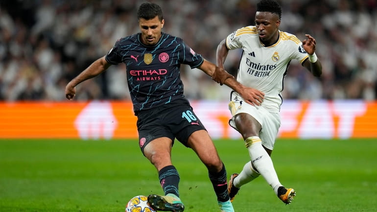 Real Madrid's Vinicius Junior fights for the ball with Manchester...