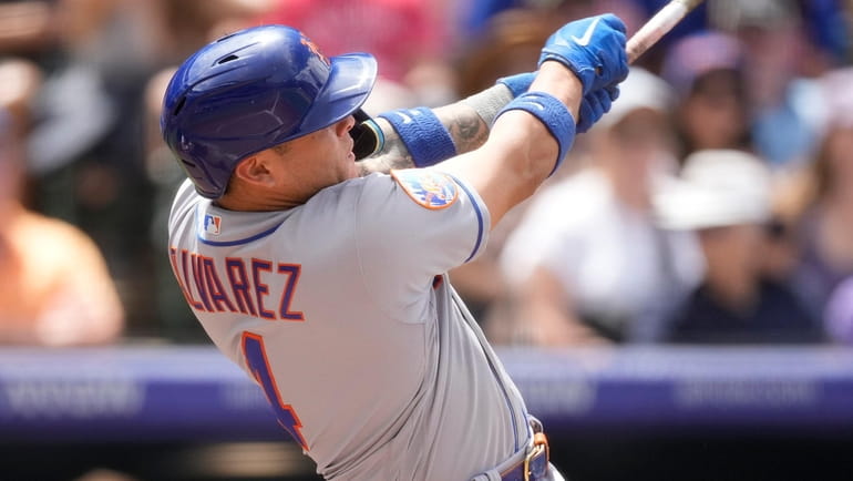 The Mets' Francisco Alvarez follows through with his swing after connecting...