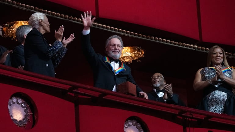 Comedian Billy Crystal, center, waves as he is applauded by...