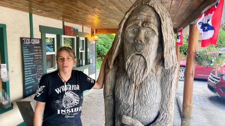 Pauline Bauer leans against a wooden statue outside Bob's Trading...