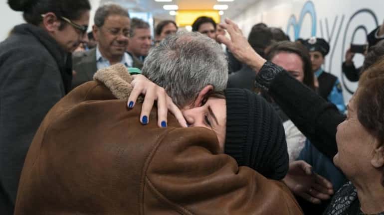 Family members who have just arrived from Syria embrace and...