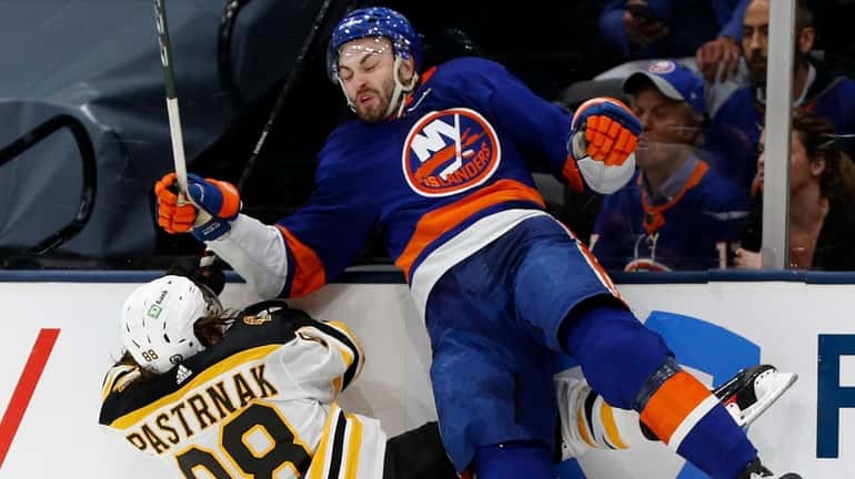 Adam Pelech of the New York Islanders checks David Pastrnak of...