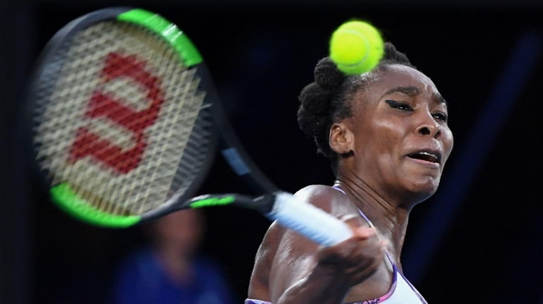 Venus Williams hits a return against Serena Williams during the...