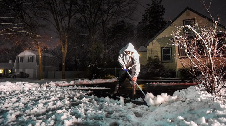 Nick Augusta shovels snow and slush in front of his...